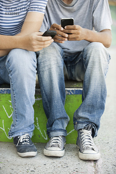 Junge Männer  die Mobiltelefone benutzen  niedrige Sektion