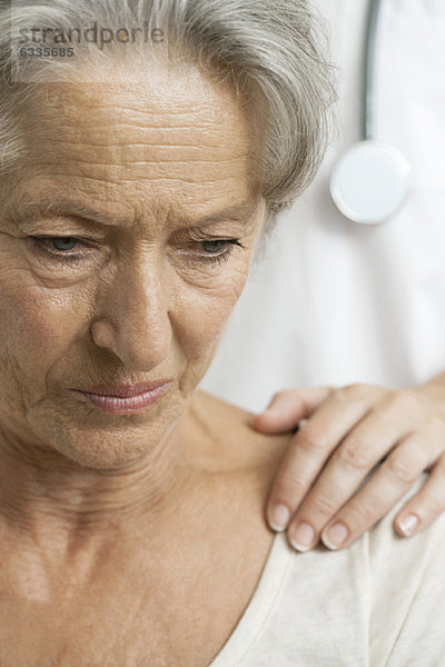 Ältere Frau  die schlechte Nachrichten von einem fürsorglichen Arzt erhält.