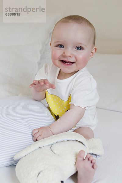 Lächelndes Baby auf dem Bett sitzend