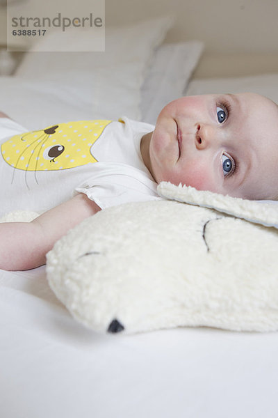 Lächelndes Baby auf dem Bett liegend