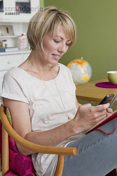 Frau mit Handy in der Küche