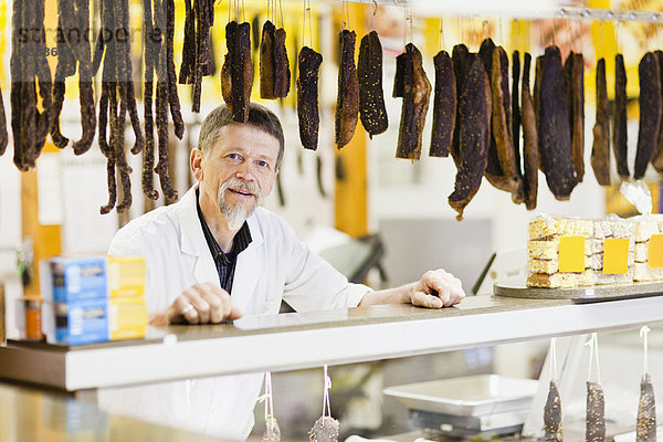 Metzger stehend an der Fleischtheke