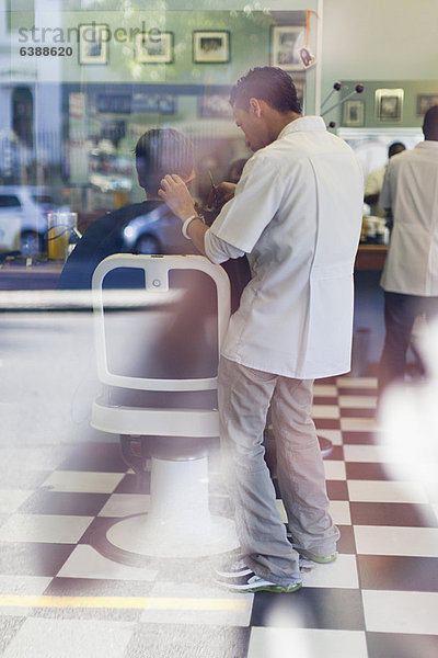 Friseur bei der Arbeit am Kunden im Geschäft