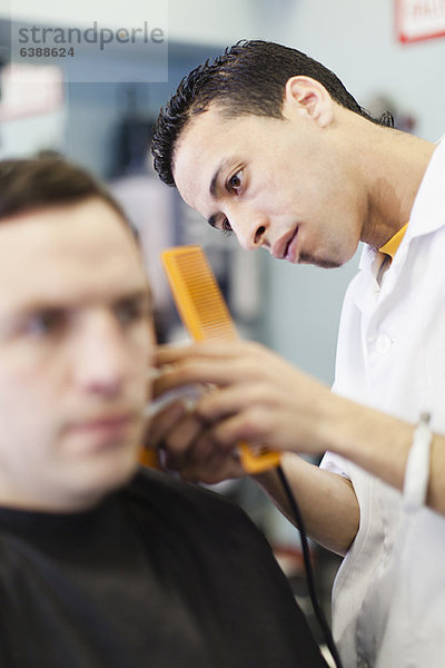 Friseur bei der Arbeit am Kunden im Geschäft