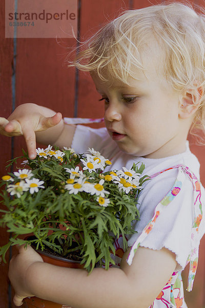 Mädchen berührt Topfpflanze im Freien