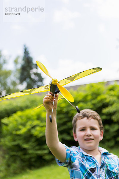 Junge spielt mit Spielzeugflugzeug im Freien