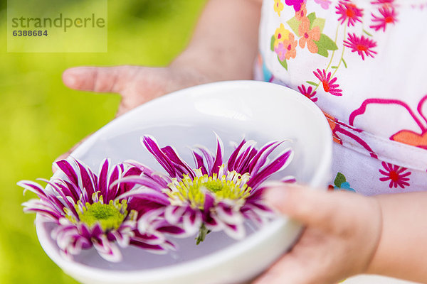 Mädchen mit Blumen in der Schale im Freien