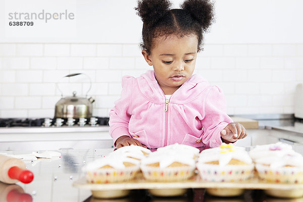 Mädchen dekorieren Muffins in der Küche