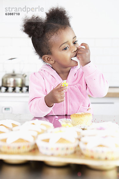 Mädchen essen Muffinglasur in der Küche