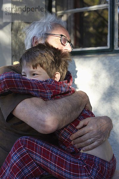 Älterer Mann umarmt Enkel im Freien