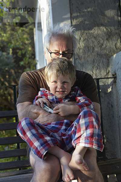 Älterer Mann umarmt Enkel im Freien
