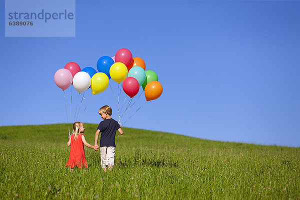 Kinder mit bunten Ballons im Gras