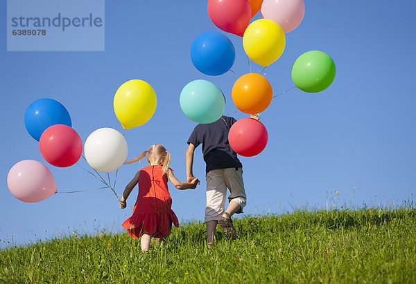 Kinder mit bunten Ballons im Gras