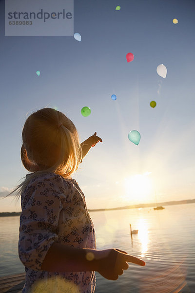 Mädchen beobachtet Ballons  die wegfliegen