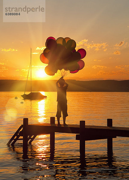 Junge hält Ballons auf Holzsteg