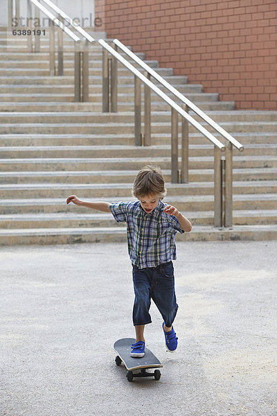 Junge spielt mit Skateboard im Freien