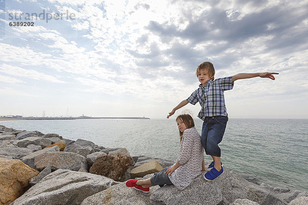 Kinder spielen auf Felsen am Strand