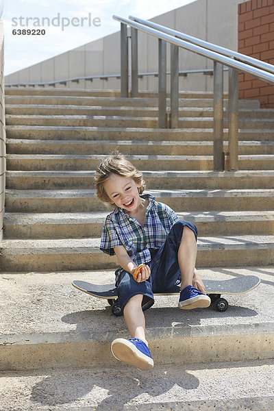 Junge sitzend auf Skateboard auf Treppe