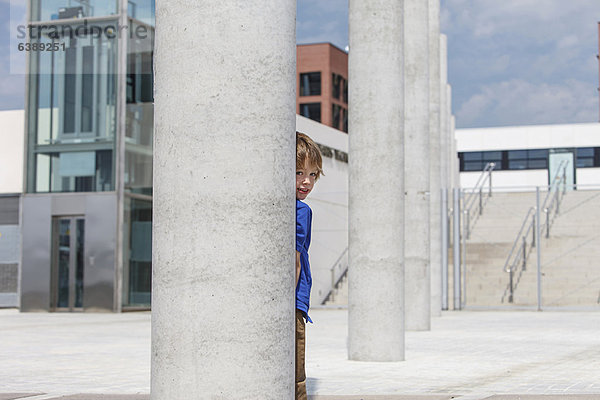 Junge blickt von hinten auf die Säule