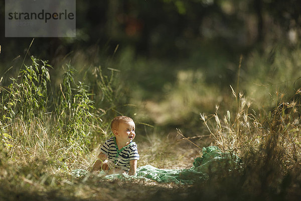 Kleinkind auf Decke im Feld sitzend