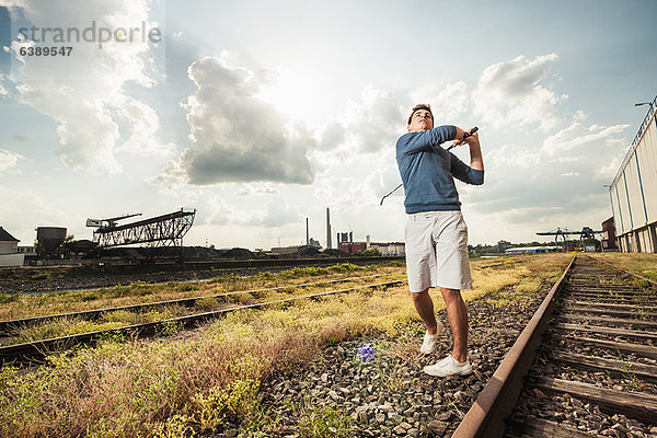 Mann spielt Golf auf Schienen