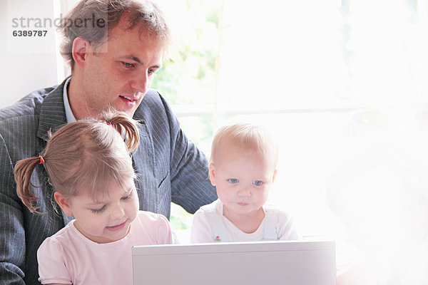 Vater und Kinder spielen mit dem Laptop