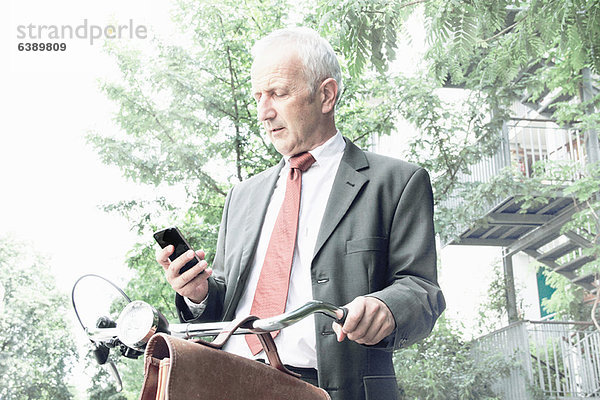 Geschäftsmann mit Handy auf dem Fahrrad