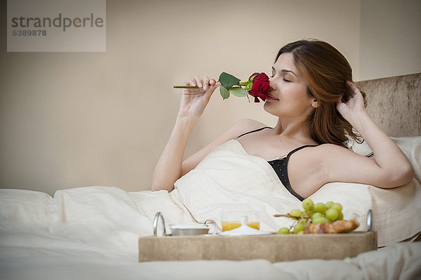 Frau entspannt mit Frühstück im Bett
