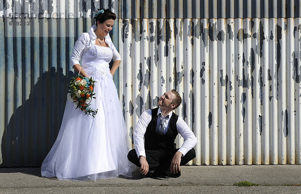 Junges Brautpaar posiert vor einer Wellblechwand