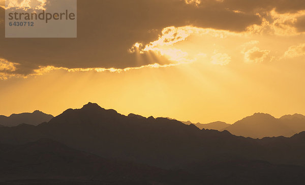 Sonnenlicht scheint durch die Wolken bei Sonnenuntergang über der Wüste Sinai  Ägypten  Afrika