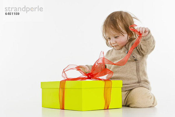 Ein kleines Mädchen  das ein Geschenk auspackt.