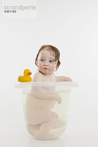 Ein kleines Mädchen in einem Eimer mit Wasser.