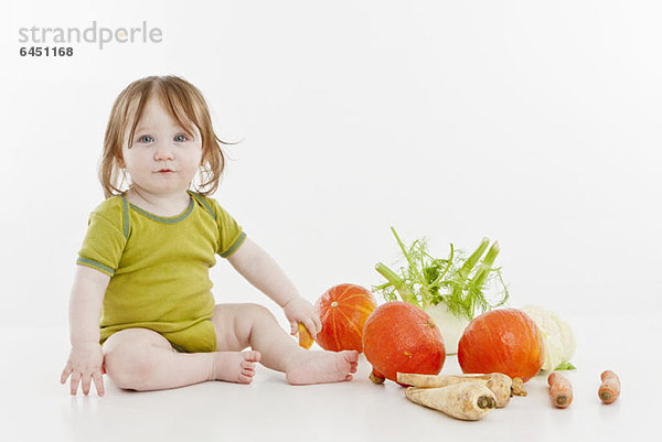 Ein kleines Mädchen sitzend mit Gemüse