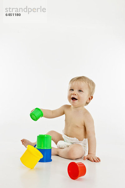 Ein kleiner Junge spielt mit Plastikbechern.