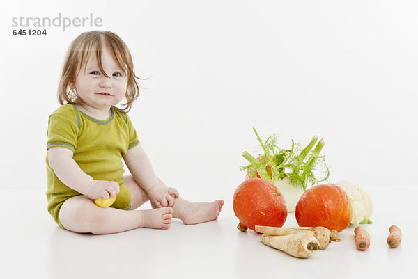 Ein kleines Mädchen sitzend mit Gemüse