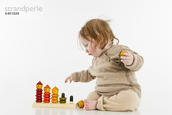 Ein kleines Mädchen spielt mit einem hölzernen Stapelspielzeug