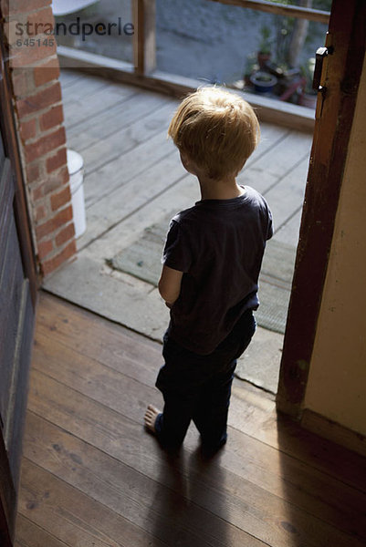 Ein kleiner Junge steht in einer offenen Tür.