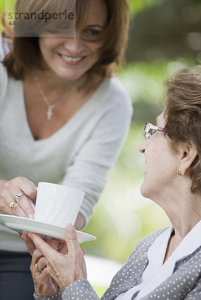 Eine Frau  die einer älteren Frau eine Tasse Tee gibt.