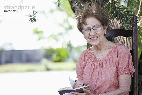 Porträt einer älteren Frau beim Schreiben in einem Buch