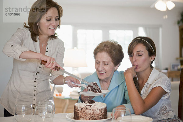 Eine Frau serviert Kuchen für ihre Mutter und Tochter.