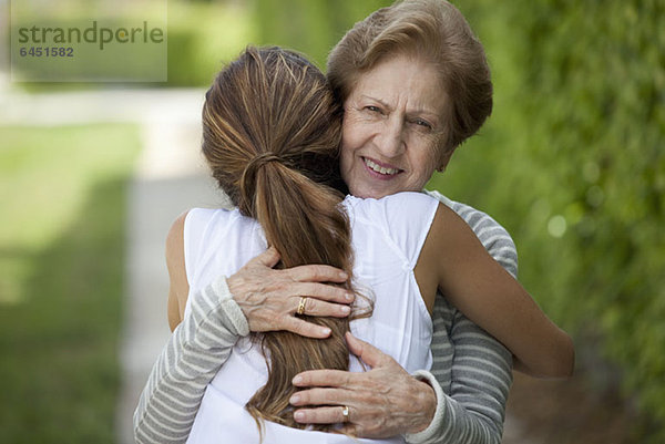 Eine ältere Frau  die eine junge Frau umarmt.