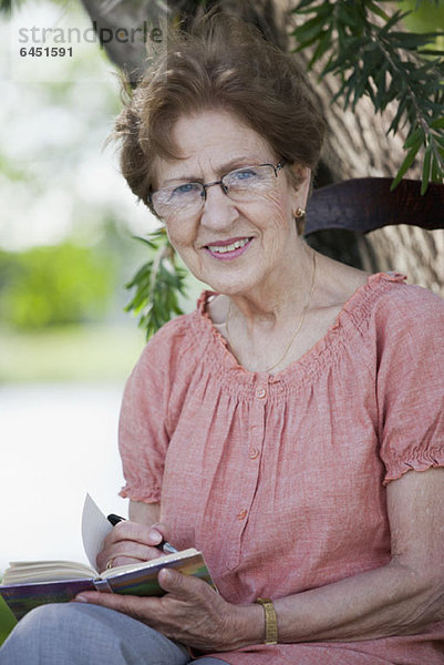 Porträt einer älteren Frau beim Schreiben in einem Buch