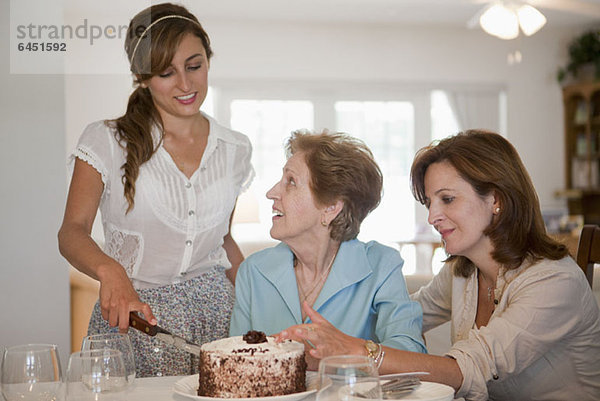 Eine junge Frau serviert Kuchen für ihre Mutter und Großmutter.