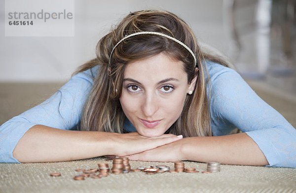 Eine Frau auf dem Boden liegend mit Stapeln von US-Münzen.