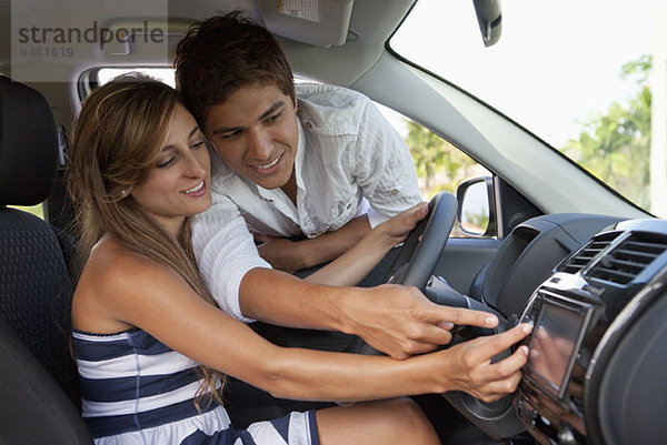 Ein Mann  der im Autofenster lehnt und seiner Freundin mit dem GPS hilft.