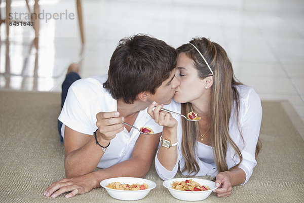 Ein junges Paar  das sich beim Frühstück küsst.