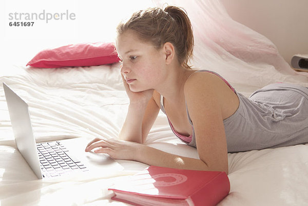 Mädchen im Bett bei den Hausaufgaben