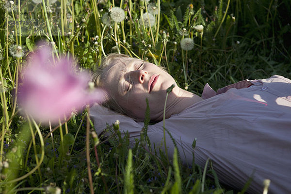 Eine Frau im Gras liegend  schlafend  Nahaufnahme