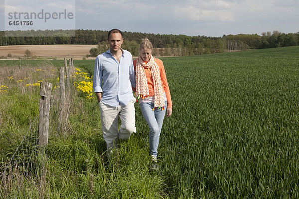 Ein Paar  das nebeneinander auf einem Feld spazieren geht.