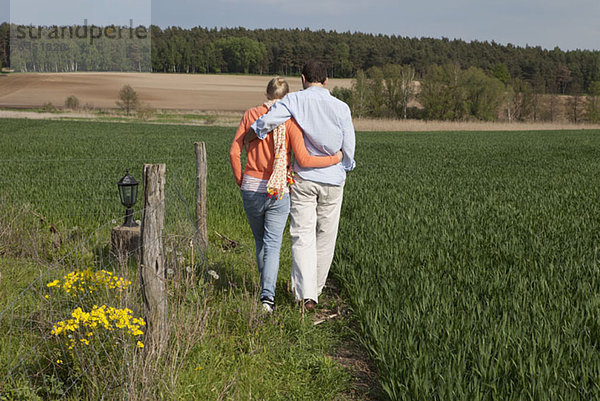 Ein Paar  das Seite an Seite auf einem Feld geht  Rückansicht